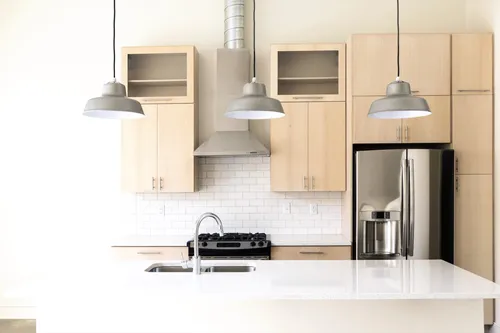 Modern kitchen with light wood cabinets and pendant lights — well-staged listing photography
