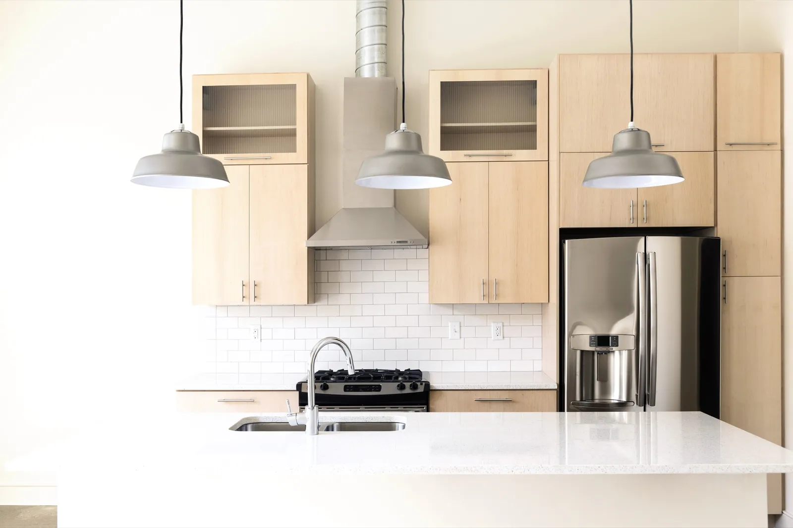 Modern kitchen with light wood cabinets and pendant lights — well-staged listing photography